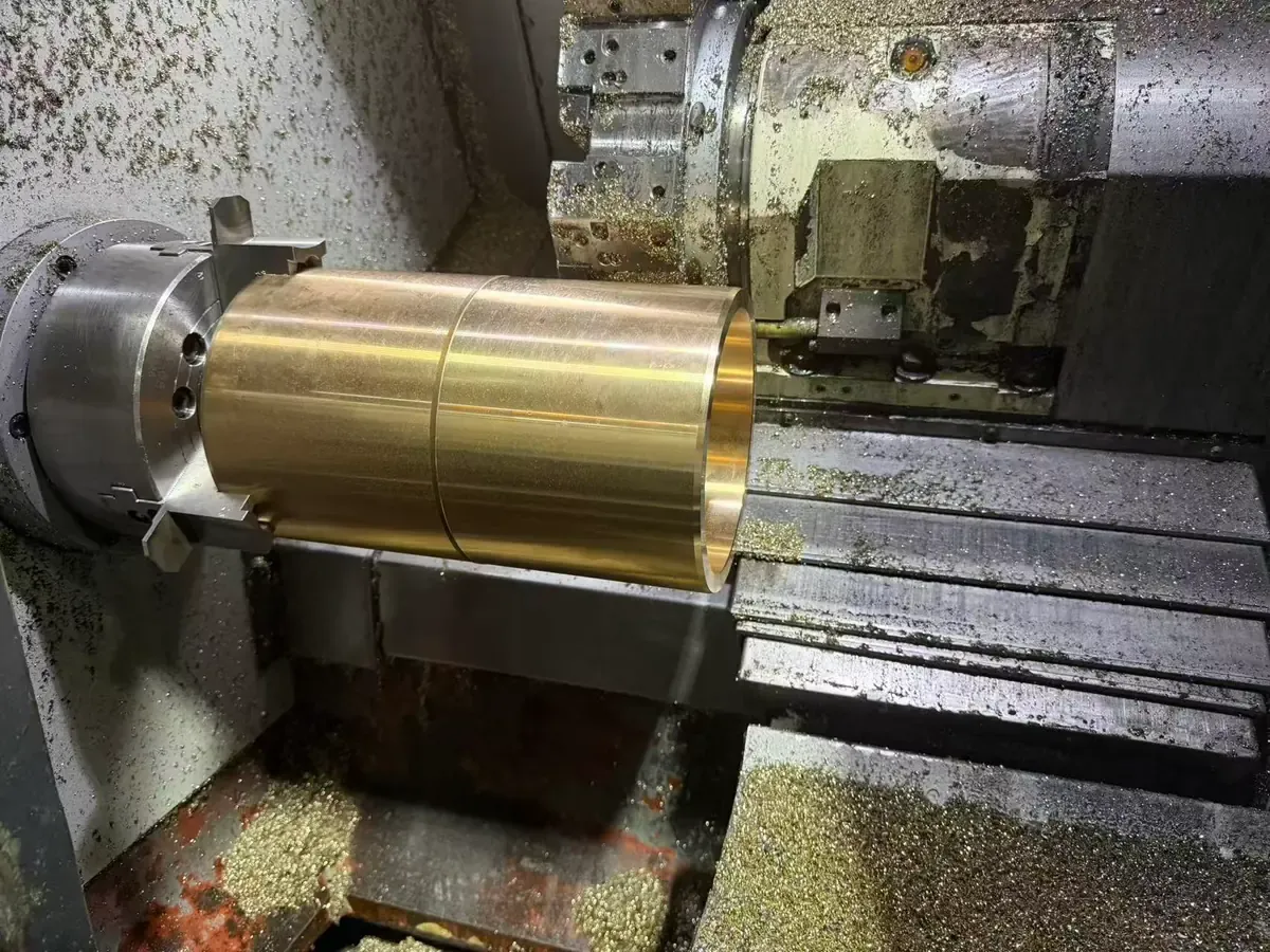 Large bronze bushing being turned on a CNC lathe at the Bushing MFG plant